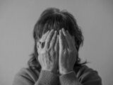 grayscale photo of woman covering face with her hands