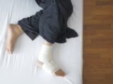 Top view of a bandaged foot resting on a bed, depicting injury and recovery.