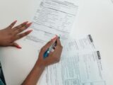 A woman with red nails fills out adoption application forms on a desk.