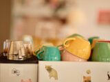 A collection of colorful coffee cups on an espresso machine in a cozy cafe setting.