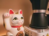 a cat figurine next to a coffee maker