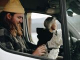 Man and woman enjoy a scenic road trip with their dog in a van.