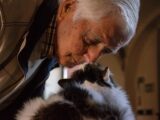 man in black and white jacket holding white and black cat