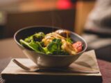 Delicious bowl of salad with fresh greens and grilled chicken served on a wooden platter.