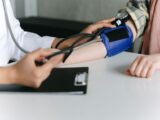 A healthcare worker uses a sphygmomanometer to check a patient's blood pressure in a medical office.